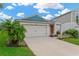 Attractive one-story house with a two-car garage, complemented by mature palm trees and landscaped front yard at 5492 Summer Sunset Dr, Apollo Beach, FL 33572