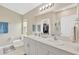 Bright bathroom with double vanity sinks, a large mirror, and a view into the walk-in closet and glass-enclosed shower at 5492 Summer Sunset Dr, Apollo Beach, FL 33572