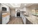 Bright kitchen featuring granite countertops, stainless steel appliances, white cabinets, and wood-look flooring at 6241 Ansley St, Spring Hill, FL 34606