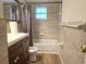Updated bathroom features a dark wood vanity and a tub with tiled walls and a window at 6317 Buster Dr, Tampa, FL 33619