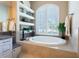 Relaxing soaking tub next to bright window and custom built-in shelving at 6933 Cozumel Ct, Land O Lakes, FL 34637