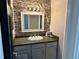 Updated powder room featuring stone accent wall, decorative mirror, and storage vanity at 7014 Doreen St, Tampa, FL 33617