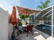 Relaxing patio area complete with an umbrella, table, and chairs near screened-in pool with lake view at 8508 Canterbury Lake Blvd, Tampa, FL 33619