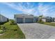Beautiful single-story home showcasing a two-car garage, paver driveway, green lawn, and beautiful landscaping at 8589 Saint Kitts Cir, Englewood, FL 34224