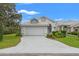 Charming single-story home with a well-manicured lawn, lush landscaping, and a two-car garage with white tile roof at 9188 Rhett Ln, Weeki Wachee, FL 34613