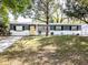 Charming single-story home with a yellow front door, beautiful lawn, and mature trees at 10233 N Valle Dr, Tampa, FL 33612