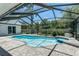 Enjoy this screened in pool with a spa, covered with brick pavers, and clear blue skies at 1028 Wyndham Way, Safety Harbor, FL 34695