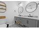 Bathroom features a double vanity with modern fixtures, decorative tile flooring, and round mirrors at 10819 Seminole N Dr, St Petersburg, FL 33708