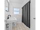 Classic bathroom with pedestal sink, black fixtures, and shower with patterned curtain at 10819 Seminole N Dr, St Petersburg, FL 33708