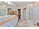 Bright bathroom features a double vanity, wood accents, soaking tub, glass shower, and a view into the walk-in closet at 1129 Emerald Hill Way, Valrico, FL 33594