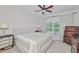 This cozy bedroom features a neutral color palette, ceiling fan, and natural light from the large window at 1129 Emerald Hill Way, Valrico, FL 33594