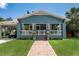 Charming blue home featuring a welcoming front porch with detailed trim and a well-manicured green lawn at 1203 E 33Rd Ave, Tampa, FL 33603