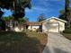 Charming single-story home with an attached garage, a well-manicured lawn, and mature trees at 12415 Stagecoach Ln, Hudson, FL 34667