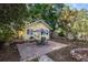 View of a yellow house with a brick patio in a large tree filled backyard, with a grill and dining area at 132 21St S Ave, St Petersburg, FL 33705