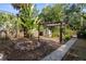 Serene backyard with lush greenery, stone walkway, fire pit, wooden pergola, and storage shed at 132 21St S Ave, St Petersburg, FL 33705