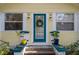 A teal door with a wreath sits between two windows on a yellow house with flowerpots on either side at 132 21St S Ave, St Petersburg, FL 33705
