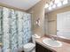 This bathroom features a single sink vanity, toilet, and shower with a decorative floral shower curtain at 13313 Ashbark Ct, Riverview, FL 33579