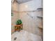 Close-up of a tiled shower with a wooden bench, a hand-held shower head, and corner shelving at 1600 Gulf Blvd # 514, Clearwater Beach, FL 33767