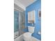 Bathroom features a shower with glass door, toilet, and cabinet on a blue wall at 2113 Malcolm Dr, Palm Harbor, FL 34684