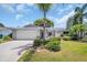 Charming single-story home featuring a lush landscaped front yard, inviting curb appeal, and a two-car garage at 2113 Malcolm Dr, Palm Harbor, FL 34684