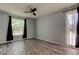 A serene bedroom with wood-look flooring, a ceiling fan, and large windows covered with black curtains at 2380 Shelly Dr # B, Palm Harbor, FL 34684