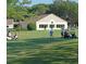 Golfers playing on a lush course with golf carts and a clubhouse in the background at 2380 Shelly Dr # B, Palm Harbor, FL 34684
