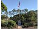 American flag with an attractive monument, lush landscaping, and clear blue skies on a sunny day at 2380 Shelly Dr # B, Palm Harbor, FL 34684
