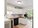 Well-lit kitchen featuring white cabinets, dark countertops, and tile backsplash at 2461 Rhodesian Dr # 37, Clearwater, FL 33763