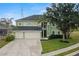 Exterior of a two-story home with an attached three-car garage, mature trees, and lawn at 2832 Brinley Dr, Trinity, FL 34655