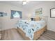 Cozy bedroom with a ceiling fan, window with drapes, and plush bedding and light, wood-look floors at 3126 Highlands Blvd # 3126, Palm Harbor, FL 34684