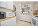 This kitchen has white cabinets, a tile floor, and a microwave, plus a peek-through to the living room at 3126 Highlands Blvd # 3126, Palm Harbor, FL 34684