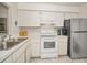 Well-lit kitchen features white cabinets, stainless steel refrigerator, oven, and decorative tile backsplash at 3126 Highlands Blvd # 3126, Palm Harbor, FL 34684