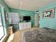 Cozy bedroom featuring bright teal walls, neutral carpet, and a white dresser with a large-screen television at 320 Medallion Blvd # G, Madeira Beach, FL 33708