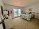Bright bedroom featuring large window, colorful bedding, and a white dresser with a large-screen television at 320 Medallion Blvd # G, Madeira Beach, FL 33708