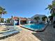 Community pool area with lounge chairs and palm trees on a bright, sunny day at 320 Medallion Blvd # G, Madeira Beach, FL 33708
