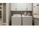 Functional laundry room with white washer and dryer, upper cabinets, and decorative accents at 3475 Silent Gardens Cv, Wesley Chapel, FL 33543