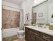 Bathroom featuring a tub with tiled walls, a dark wood vanity, and a large mirror at 4918 Lakeshore Oaks Ct, Tampa, FL 33624