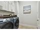 Bright laundry room features white cabinets, dark countertop, mosaic backsplash, and modern appliances at 4918 Lakeshore Oaks Ct, Tampa, FL 33624