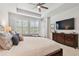 Main bedroom with shuttered windows, a TV, a ceiling fan, and an open view to the bathroom at 4918 Lakeshore Oaks Ct, Tampa, FL 33624
