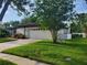 Inviting home with a two-car garage, lush green lawn, and mature trees providing ample shade and curb appeal at 50 Water Oak Way, Oldsmar, FL 34677