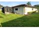 View of home exterior with a screened patio and a well-maintained lawn with neatly trimmed hedges and shrubs at 50 Water Oak Way, Oldsmar, FL 34677