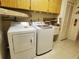 Convenient laundry area features modern white washer and dryer, plus storage cabinets at 50 Water Oak Way, Oldsmar, FL 34677