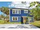 Blue two-story home with a bright yellow front door, solar panels and mature landscaping at 5632 Indiana Ave, New Port Richey, FL 34652