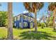 Beautiful home with blue siding, white trim, a yellow front door, and palm tree landscaping at 5632 Indiana Ave, New Port Richey, FL 34652