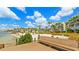 Beautiful beach view with tiki umbrellas in front of beachfront condos, with beach access from a deck and bench at 6021 Bahia Del Mar Cir # 239, St Petersburg, FL 33715