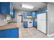 Bright kitchen features blue cabinets, white appliances, tile flooring, and gray walls at 6208 Florida E Cir, Apollo Beach, FL 33572