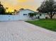 View of the cream-colored exterior and brick paver driveway of this well-maintained home at sunset at 6235 17Th N Ave, St Petersburg, FL 33710