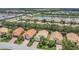 Aerial view of a community with terracotta tile roofs, mature trees and green lawns near a small lake at 6315 43Rd E Ct, Sarasota, FL 34243