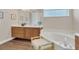 Bright bathroom with a soaking tub, wood cabinets, a vanity and a separate area with a glass window at 6315 43Rd E Ct, Sarasota, FL 34243