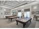 Spacious game room featuring three pool tables under soft pendant lighting with patterned grey carpet at 6315 43Rd E Ct, Sarasota, FL 34243